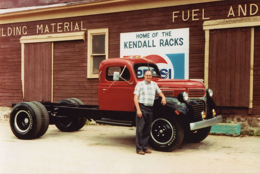 Allan Martin next to old Dodge truck by Home of the Kendall Racks Pepsi sign.